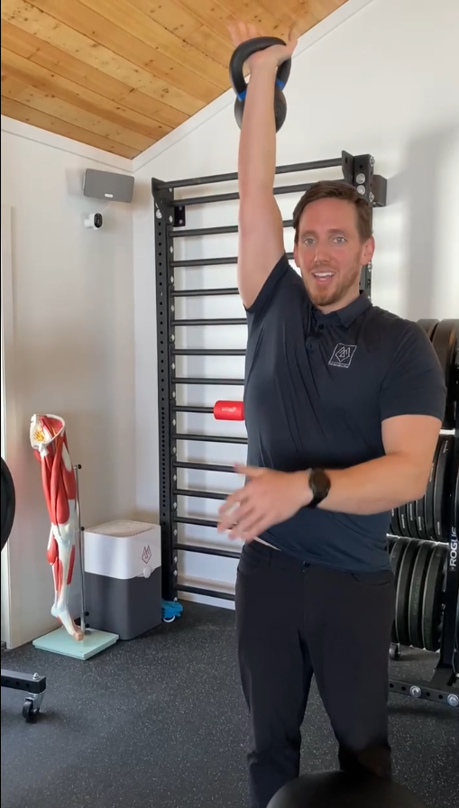 Dr. Hogan demonstrating overhead carry exercise by lifting kettle bell